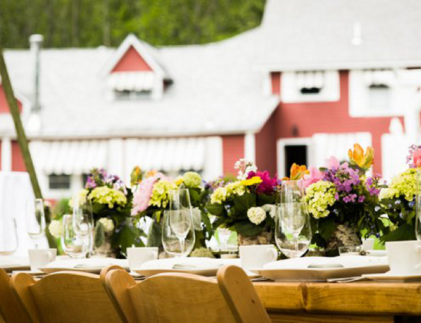 Table decorated with wine glasses and floral arrangements with exterior of inn in background