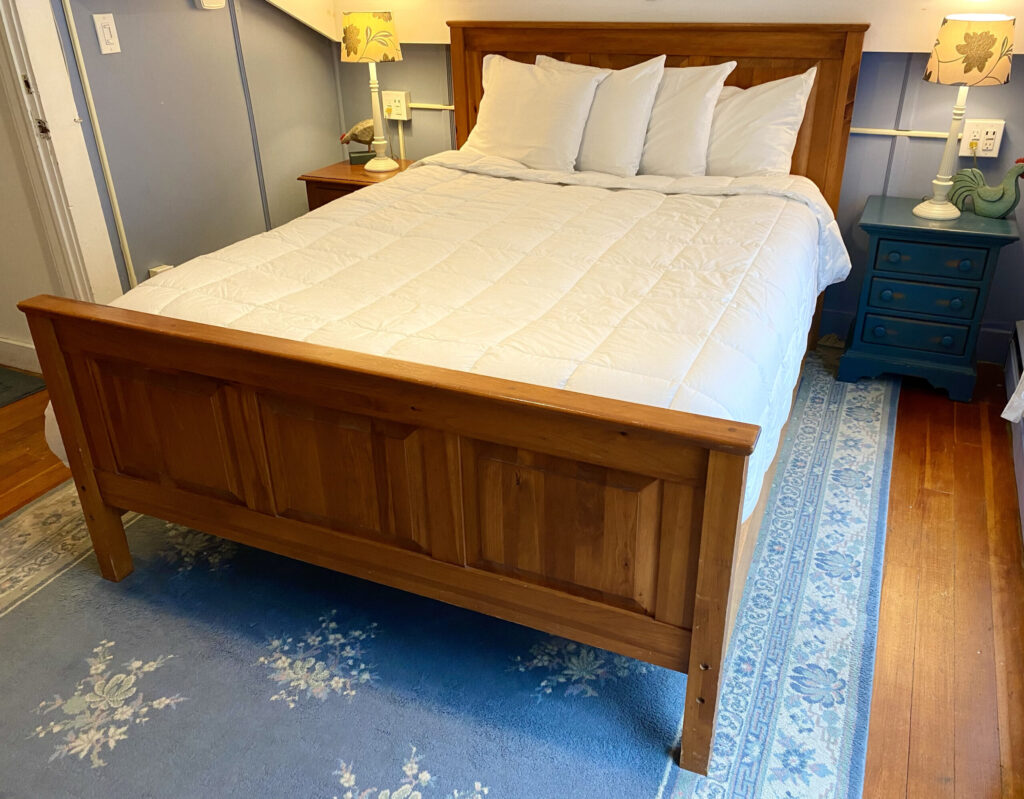 Maple bed with white comforter and pillows and blue carpet