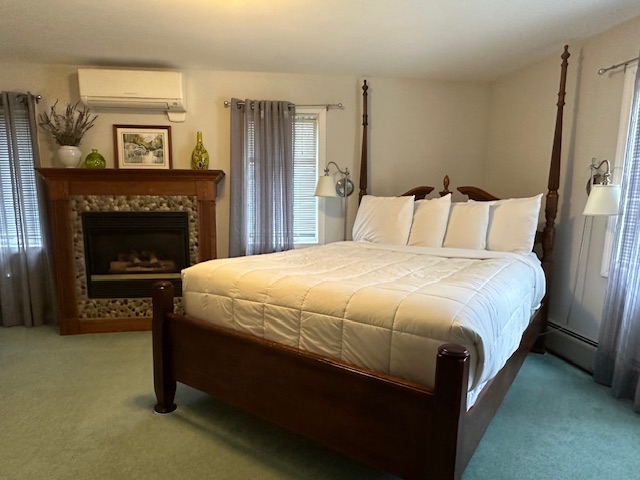 Two poster bed with white comforter and fireplace to left of bed