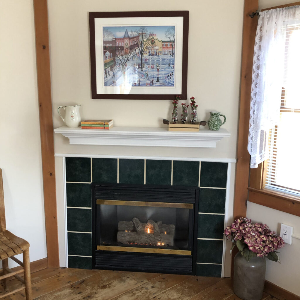 Dark tiled fireplace, white mantel, and old Currier and Ives Print above mantle
