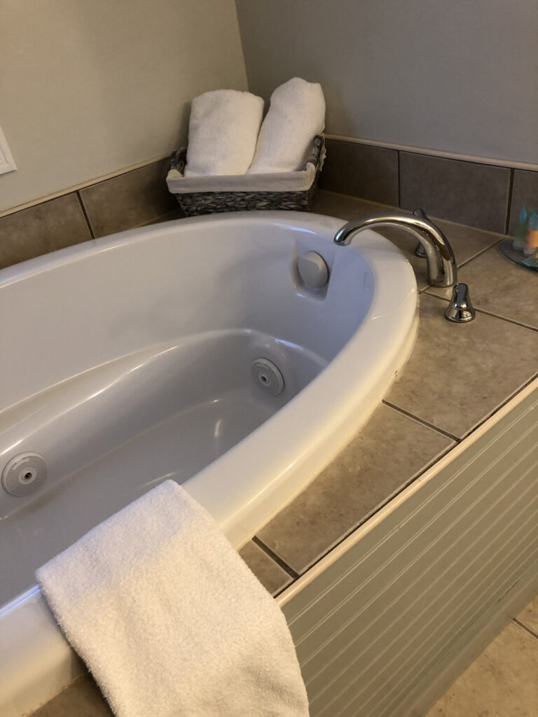 Whilpool tub with towels rolled up in corner.
